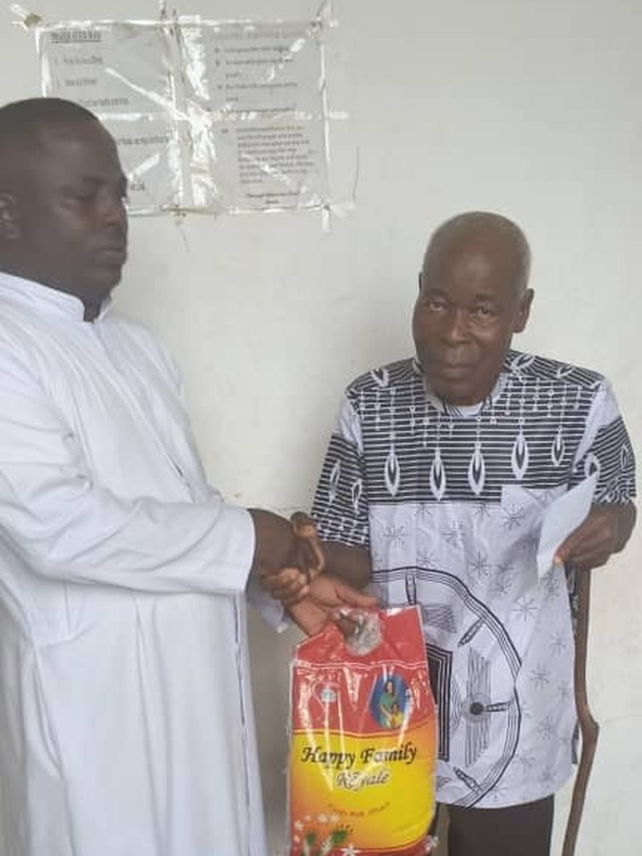 Rev. Fr. Charles Bekpar handing out support during an early ministry outreach